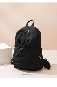 Detail of minimalist black nylon backpack with drawstring pocket and metallic zippers