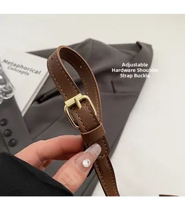 Close-up of adjustable golden metal buckle on brown leather bag shoulder strap