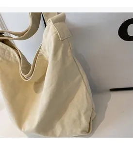 Detailed view of the coarse-grain cream canvas fabric and wide shoulder strap of the tote bag