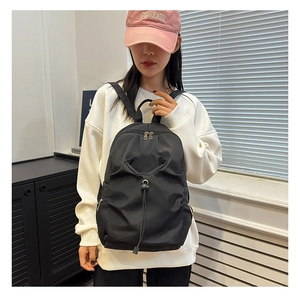 Detail of black waterproof nylon backpack featuring drawstring front and pleated design