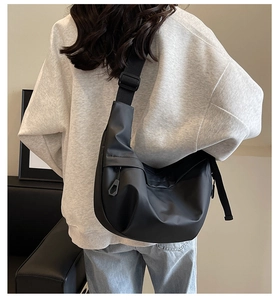 Detailed back view of a black nylon crossbody dumpling bag with wide shoulder strap