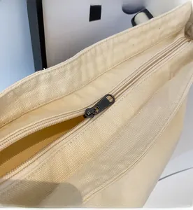 Detailed close-up showing the smooth grey metal zipper on a beige canvas tote bag