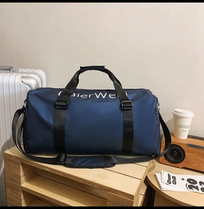 Detail view of a large navy blue waterproof travel bag styled with a suitcase and coffee