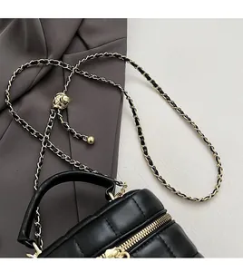 Detail of black quilted leather handbag with premium golden chain strap and top handle