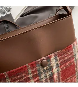 Detail of brown faux leather and red plaid tweed tote bag with gold logo lettering