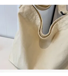 Detailed close-up of beige cotton canvas tote bag with adjustable shoulder strap and texture