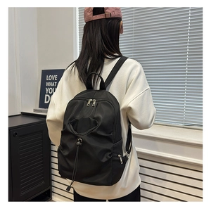 Detail view of the water-resistant black fashion backpack with drawstring front pocket