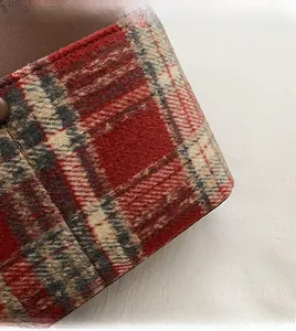 Detailed view of red plaid fabric and brown leather stitching on a bucket bag