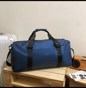 Detail of dark blue Oxford cloth travel bag on wooden stand with travel accessories