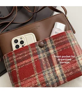Detailed view of the front plaid pocket and gold lettering on the brown shoulder bag