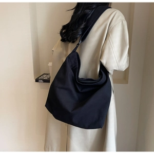 Side view of large black canvas tote bag showing size and capacity on a female model