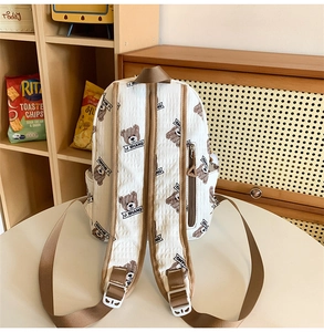 Detail of white quilted backpack with brown straps and cute bear patterns on a desk
