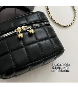 Close-up of black quilted leather bucket bag with gold chain and dual sphere zippers