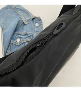 Close-up of the smooth black zipper and matte nylon fabric texture on a crossbody bag