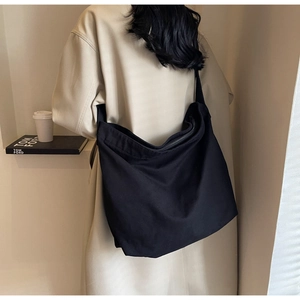 Detail of a large black canvas crossbody hobo bag featuring a secure zipper closure