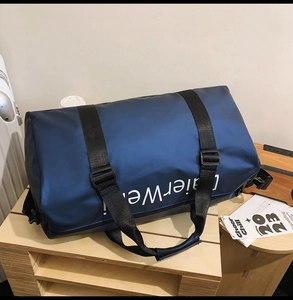 Detail of navy oxford travel bag showing wide nylon strap and large white lettering
