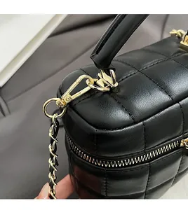 Detail of black quilted bucket bag featuring gold spring hooks and smooth leather texture