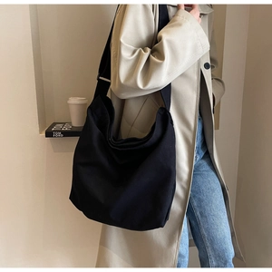 Detailed view of the large black canvas hobo bag with a wide strap on a model's shoulder