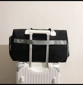 Détail du sac de voyage noir en oxford fixé à la poignée d'une valise blanche rigide