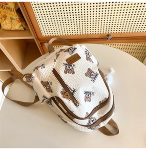 Detail of white wrinkled fabric backpack with brown bear prints and J SHANG logo brand