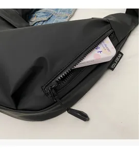 Close-up of black nylon shoulder bag featuring zippered side pocket and brand woven label