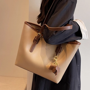 Minimalist beige tote bag with brown straps and elephant charm accessory