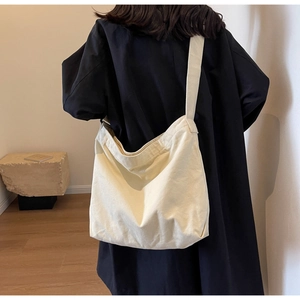 Rear view of cream canvas hobo tote bag with wide strap and minimalist drape effect