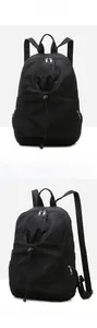 Detail of black nylon backpack featuring drawstring closure and side zipper pockets