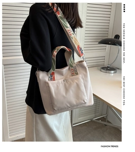 Detail of beige nylon tote bag with floral embroidered strap and front snap pocket