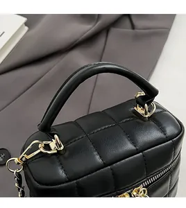 Detail of black quilted leather handbag with gold metal handle and chain strap