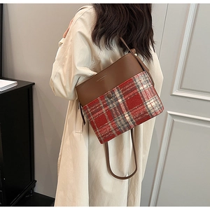 Brown leather and plaid patchwork bucket bag shown on model with beige trench coat