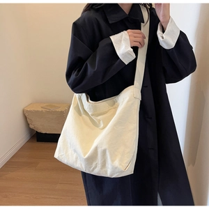 Close-up of a cream canvas tote bag worn with a black coat for professional daily commute