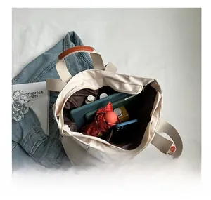 Macro della grande capacità di una borsa tote in nylon beige con articoli per uso quotidiano