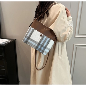 Detail of retro patchwork bucket bag featuring textured plaid fabric and leather finish