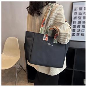 Dettaglio borsa tote in nylon nero con spalline in tessuto a stampa floreale vivace