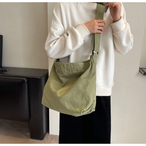 Macro view of avocado green canvas tote bag featuring an adjustable wide shoulder strap