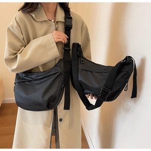Detail of black nylon crescent crossbody bag featuring adjustable strap and plastic buckle
