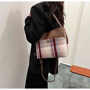 Close-up of retro plaid wool and brown leather bucket bag with adjustable shoulder strap