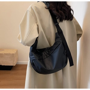Detail view of black nylon crescent bag with wide adjustable strap on a model back