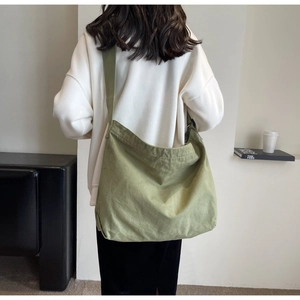Rear view of an olive green canvas hobo tote bag with a wide adjustable shoulder strap