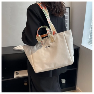Dettaglio della borsa tote in nylon bianco con tracolla floreale e logo ricamato nero