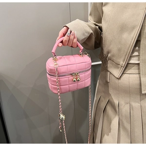 Detail of pink quilted handbag with gold chain strap and decorative zipper beads