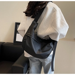 Detail of adjustable wide shoulder strap on a black nylon crossbody dumpling bag