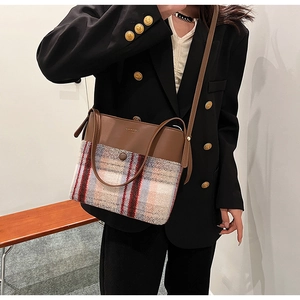 Detail of plaid wool crossbody bag with brown leather trim worn with black blazer