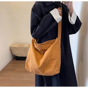 Close-up of ginger yellow canvas hobo bag with wide strap and minimalist design