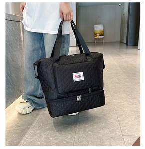 Detail of black quilted travel bag with independent shoe compartment and dual handles