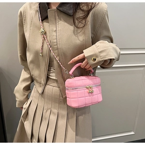 Pink quilted bucket bag with chain strap styled with a beige trench coat and pleated skirt