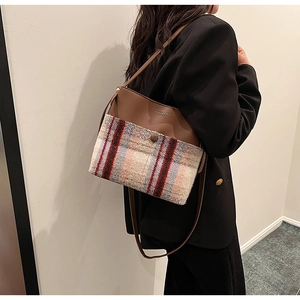 Detail of checkered woolen plaid shoulder bag worn by model with leather strap view