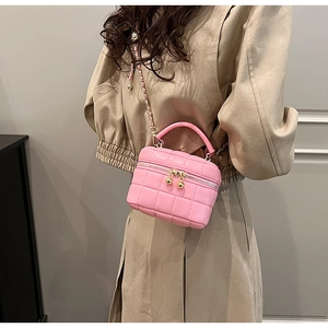Detail of pink quilted leather vanity bag featuring a gold chain strap with a metal ball charm