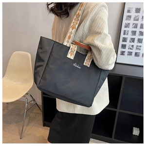 Dettaglio della borsa tote nera in nylon con spalline larghe a fantasia etnica colorata